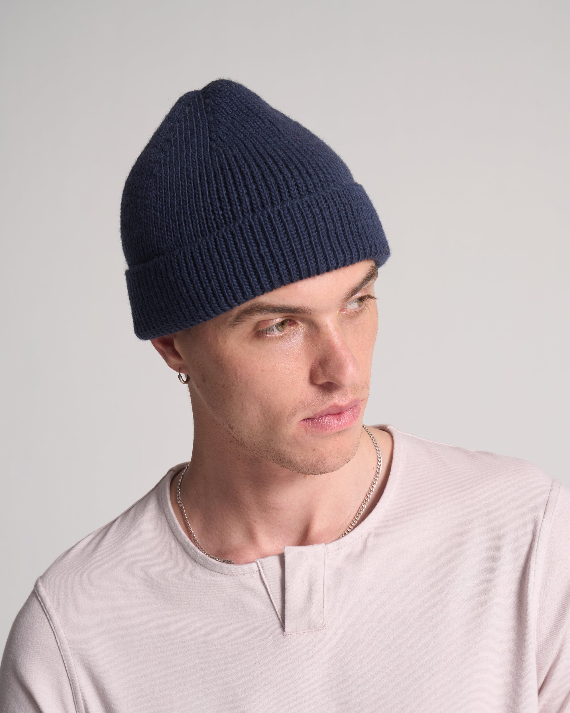 Person wearing a navy blue beanie against a light gray background