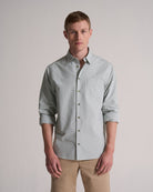 Man wearing a light green button-up shirt with rolled-up sleeves against a plain background