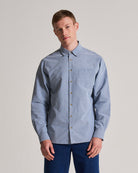 Man wearing a light blue button-up shirt against a plain background