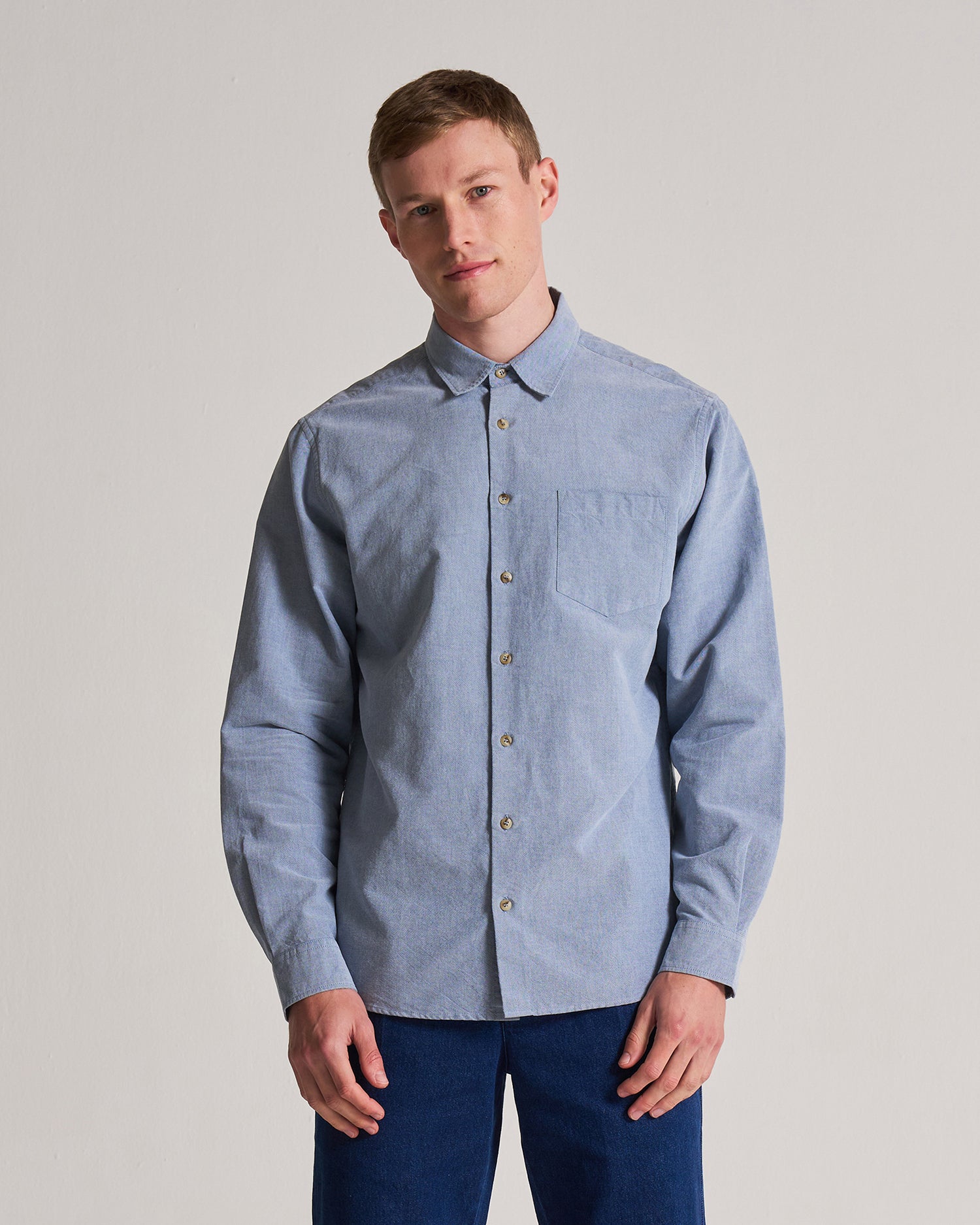 Man wearing a light blue button-up shirt against a plain background