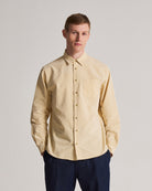 Man wearing a rattan shirt and dark pants against a plain background
