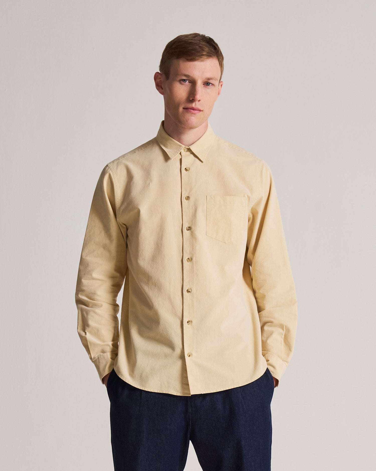 Man wearing a rattan shirt and dark pants against a plain background