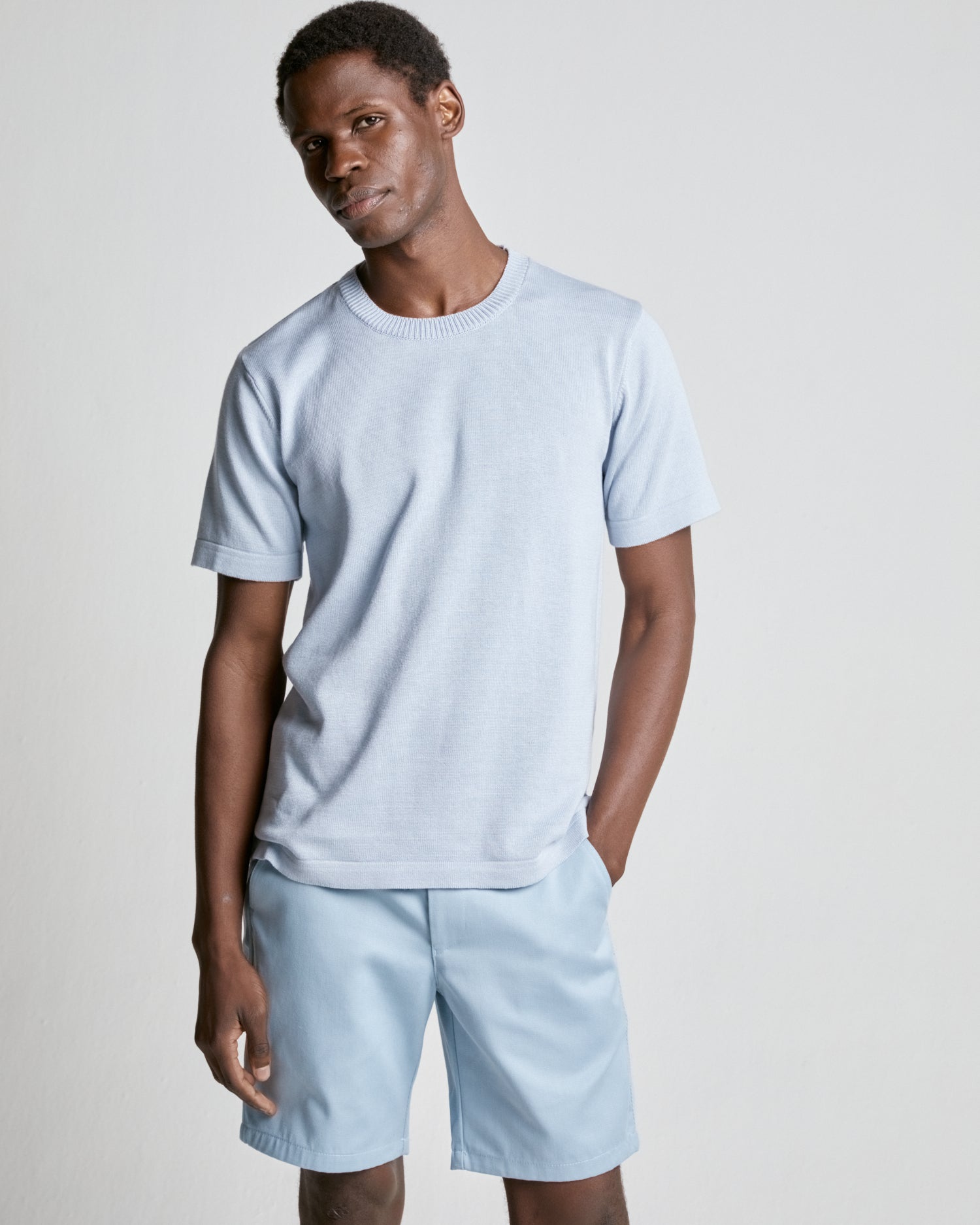 A person wearing a light blue (Zen Blue) knitted tee and matching shorts, standing against a plain background.