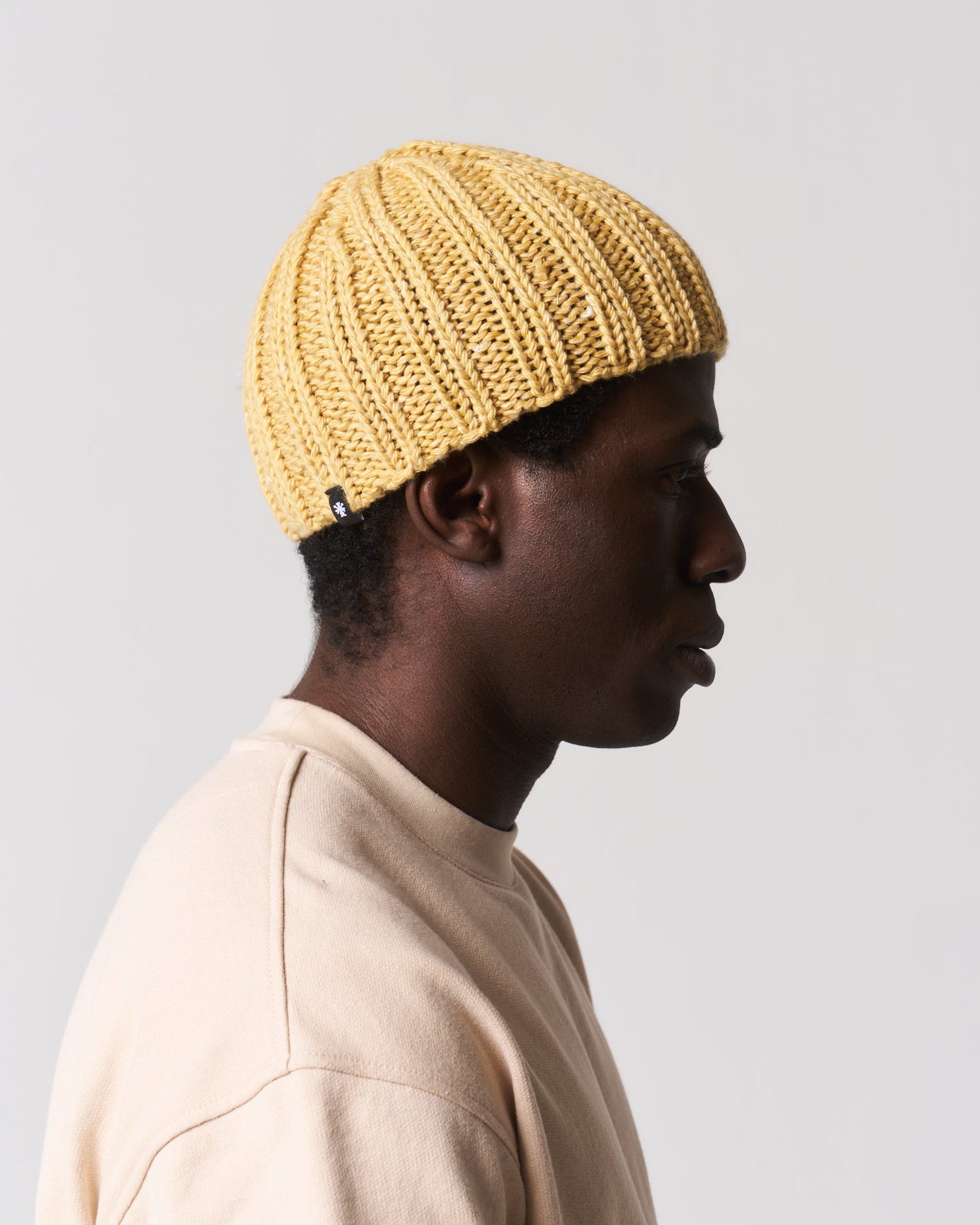 yellow knit beanie worn by a man in a beige top