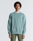 A person wearing a green, sea-spray, crew neck, long-sleeved simple sweater.