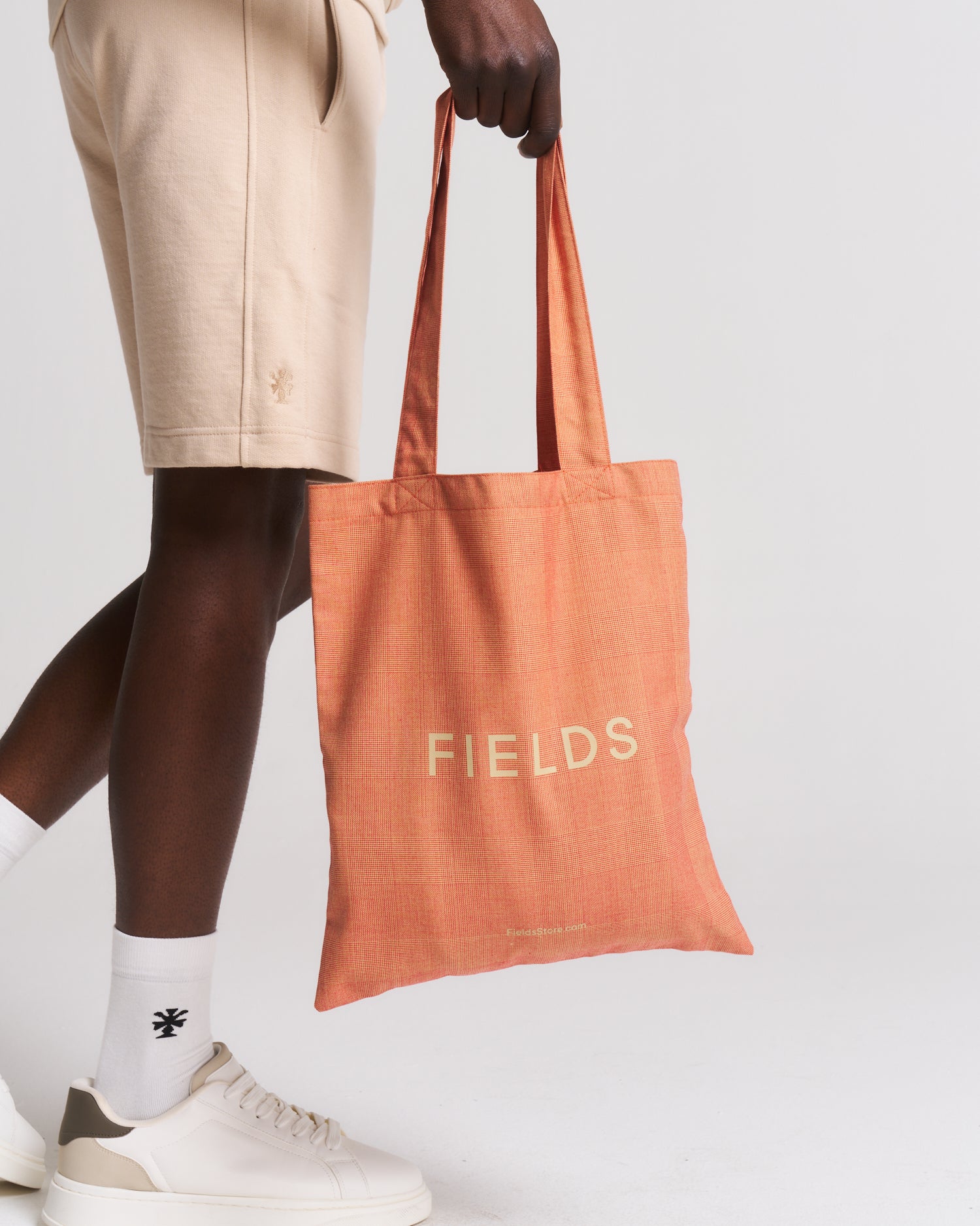 man in beige carrying an orange bag