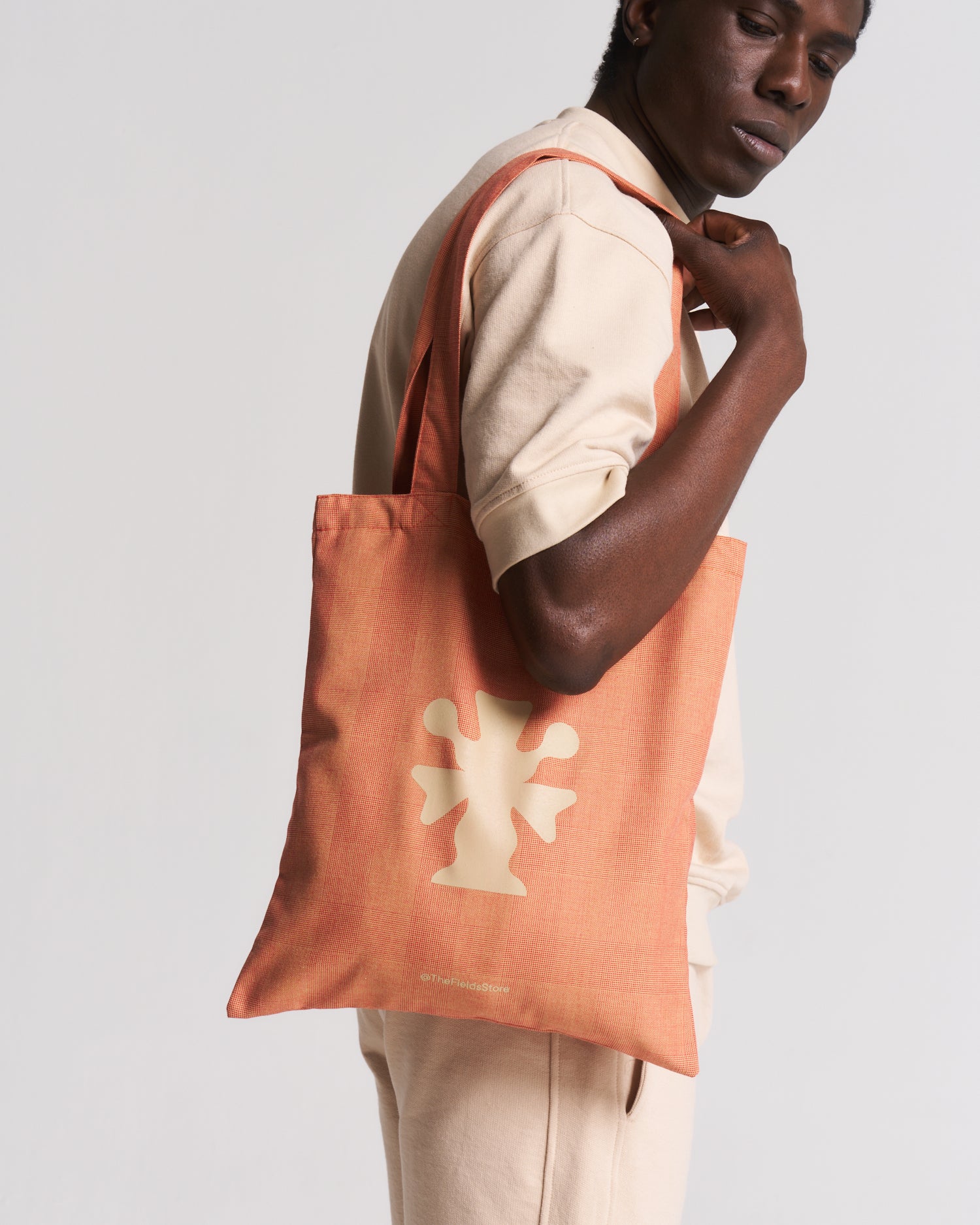 man in beige carrying an orange bag