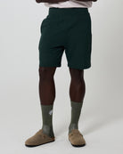 Person wearing dark green lounge shorts, olive socks, and tan shoes on a white background. Clothing from Fields. 
