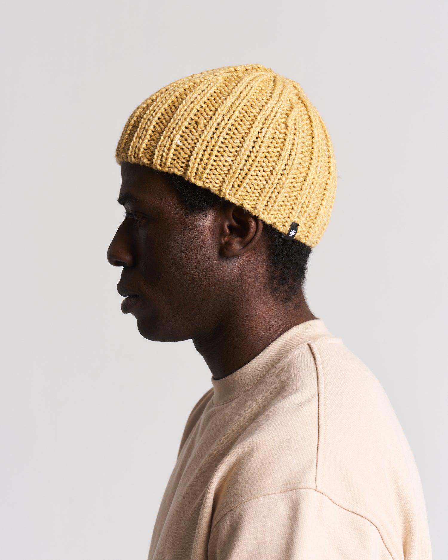 yellow knit beanie worn by a man in a beige top
