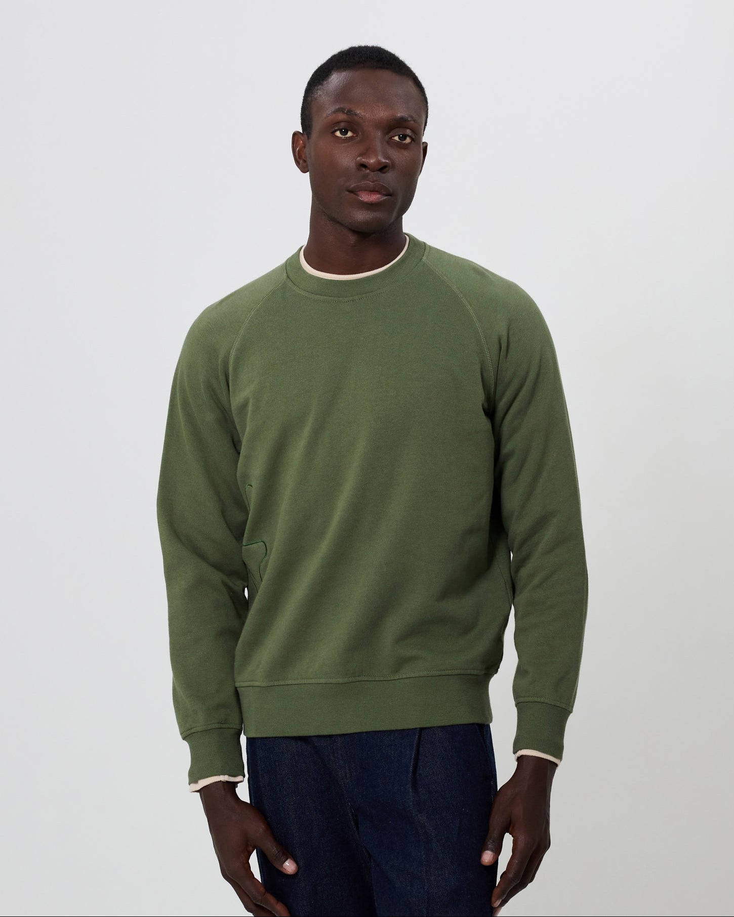 Man wearing an olive green sweatshirt against a plain background. From Fields