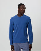 Man wearing a blue long-sleeve t-shirt with grey pants against a plain background. All from Fields. 
